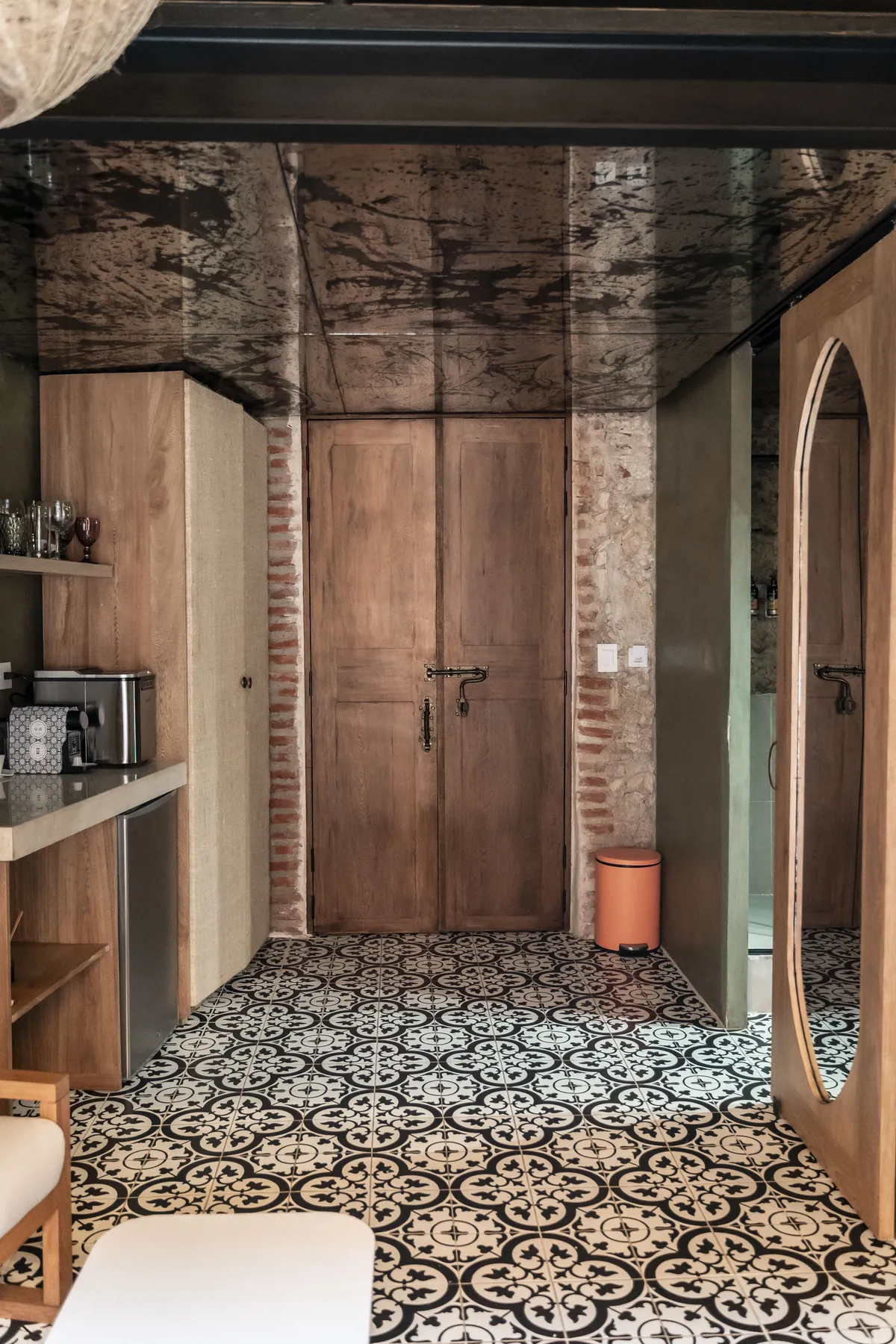 Cocineta de la habitación con cafetera, puerta de madera maciza y muro de ladrillo a la vista.